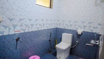 A bathroom with a geometric tile pattern, a toilet, a shower, and three buckets labeled "JOYO".