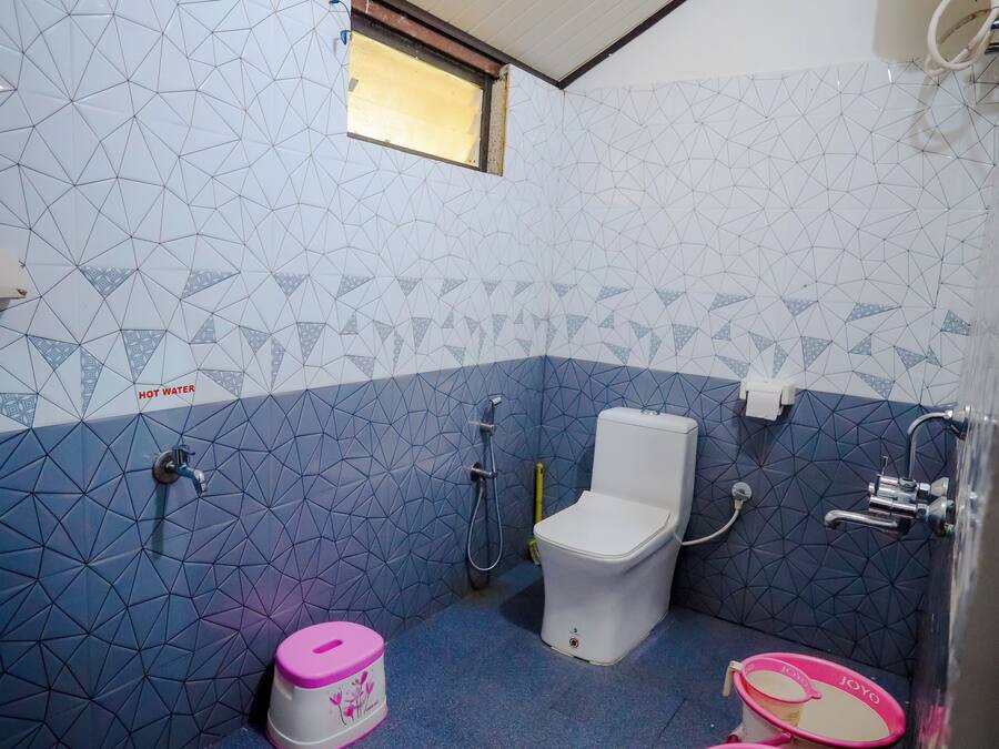 A bathroom with a geometric tile pattern, a toilet, a shower, and three buckets labeled "JOYO".
