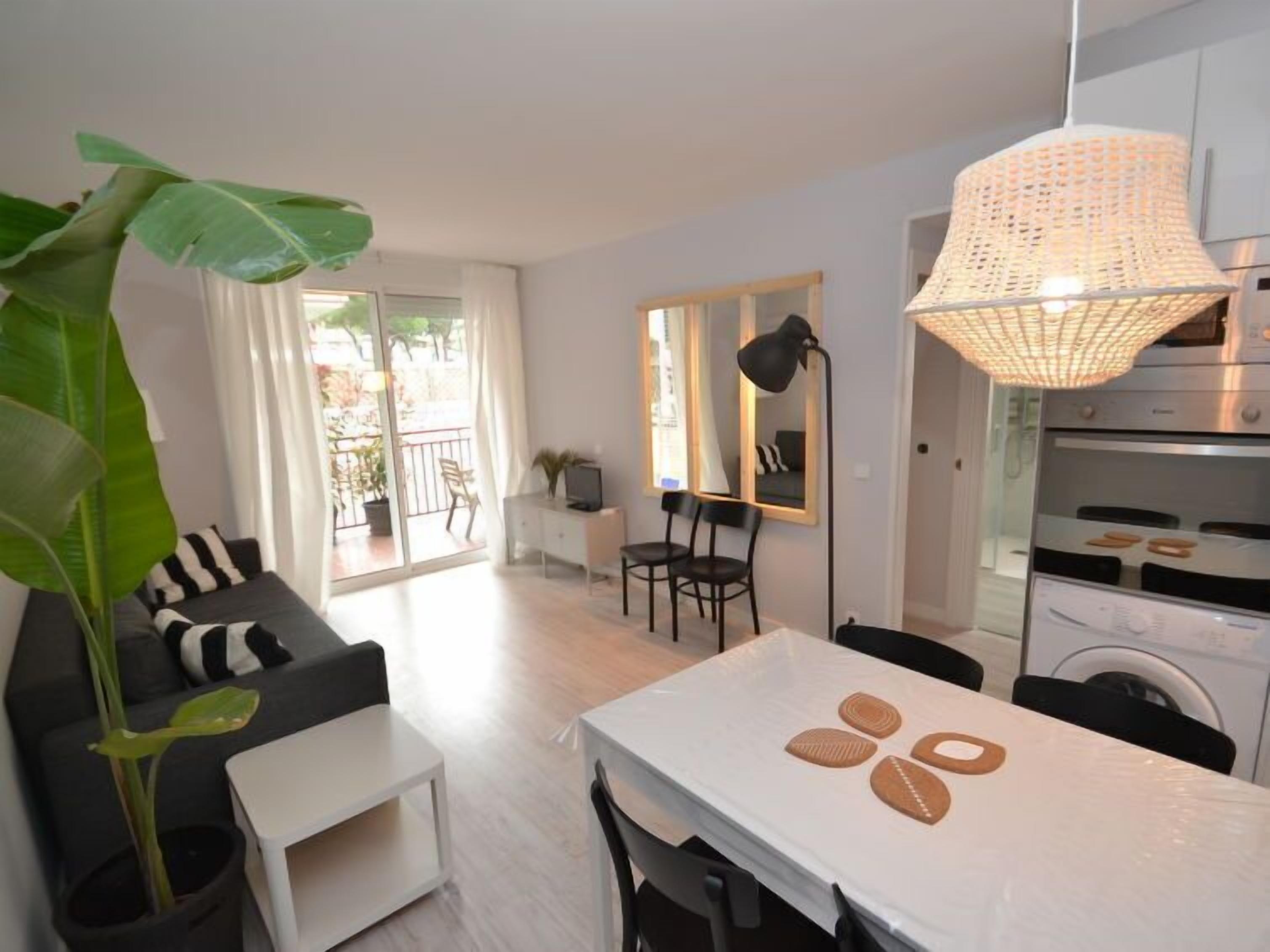 Een modern appartement met een eethoek, keuken en een balkon met planten.