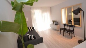 Ein modernes Wohnzimmer mit einer Couch, Sesseln, einem großen Spiegel und einer Pflanze.