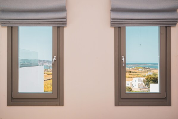 Two windows with a view of a coastal landscape and buildings. - Kouros Blanc Resort & Suites (Paros)