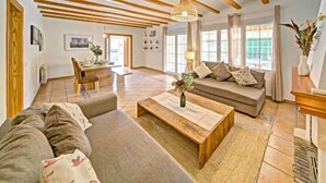 A spacious living room with a wooden ceiling, a sofa set, a coffee table, and a dining area with a chair and table. - Vacation home La Sal by Interhome (Moraira)