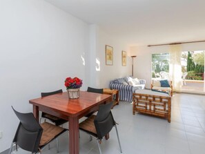 A modern living room with a wooden dining table, black chairs, a sofa, and a bed.