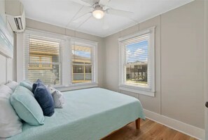 A bedroom with a bed, a ceiling fan, and windows with blinds. - Steps to the Beach, Ocean Views, Ocean front lot (Carolina Beach)