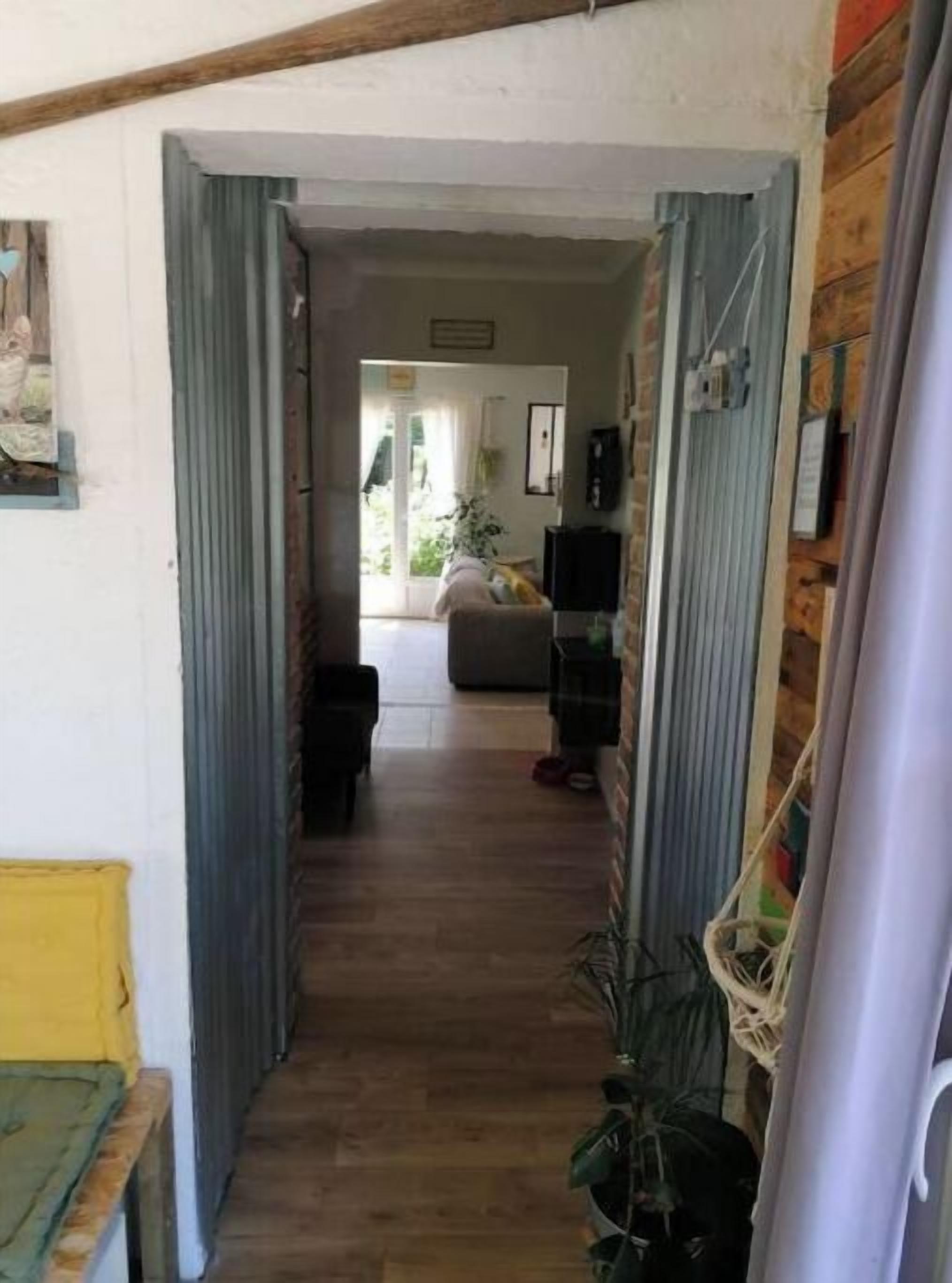 Un pasillo estrecho que conduce a una sala de estar con un sofá, un televisor y una planta.