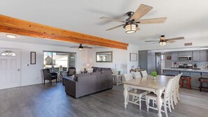 A spacious living area with a dining table, sofas, and ceiling fans. - Desert Home w/ Pool & Spa + Games (Lake Havasu City)