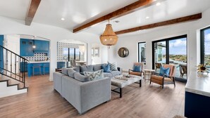 A spacious living area with a grey sofa, blue and brown chairs, a coffee table, and a large window offering a view of the outdoors. - *New PK SLIDE* 5 bed, 6 bath home with pool/hot tub. Hell's Gate View!! (Strawn)