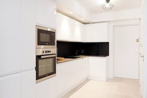 Una cucina moderna con mobili bianchi, forno integrato e microonde.