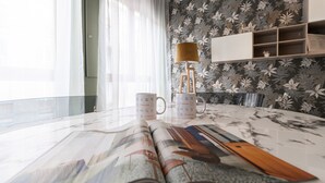 A modern living room with a glass table, two Italianway mugs, a lamp, and a floral wallpaper. - Italianway Collection - Cannobio 8 - Traviata (Milan)