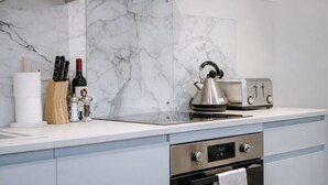 Una cucina moderna con zoccolo in marmo, bollitore, tostapane e orologio digitale per il forno.
