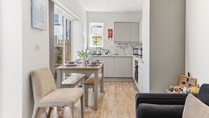 A modern kitchen with a dining area, a sofa, and a bookshelf. - Beautiful central Harrogate Flat (North Yorkshire)