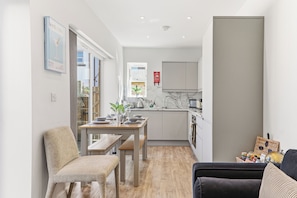 A compact kitchen with a dining area, a sofa, and a small table with chairs. - Beautiful central Harrogate Flat (North Yorkshire)