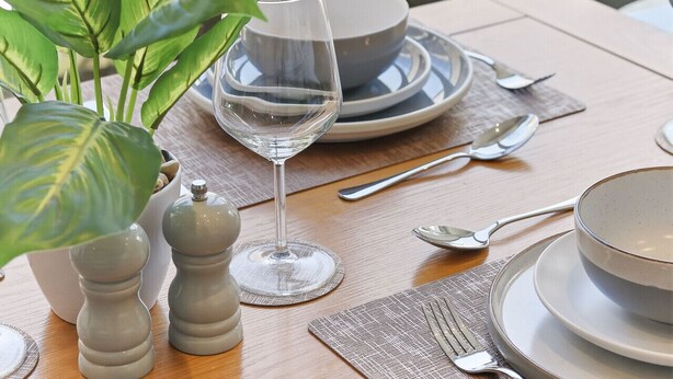 A dining table set with plates, cutlery, a glass, and a plant. - Beautiful central Harrogate Flat (North Yorkshire)