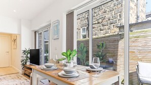 A dining area with a wooden table, chairs, and a TV. - Beautiful central Harrogate Flat (North Yorkshire)