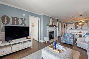 A living room with a flat-screen TV, a fireplace, and a dining area with a table and chairs.