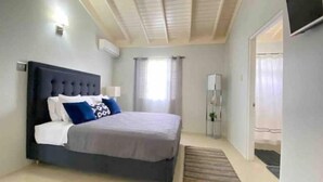 Een slaapkamer met een bed, nachtkastje, spiegel en deur.