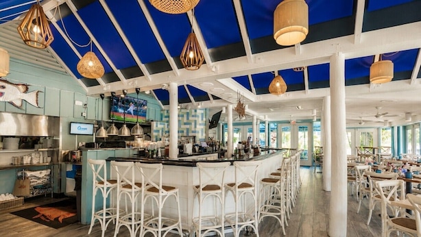 Ein Restaurant mit Barbereich, weißen Korbstühlen und einer blau-weißen Farbgestaltung.