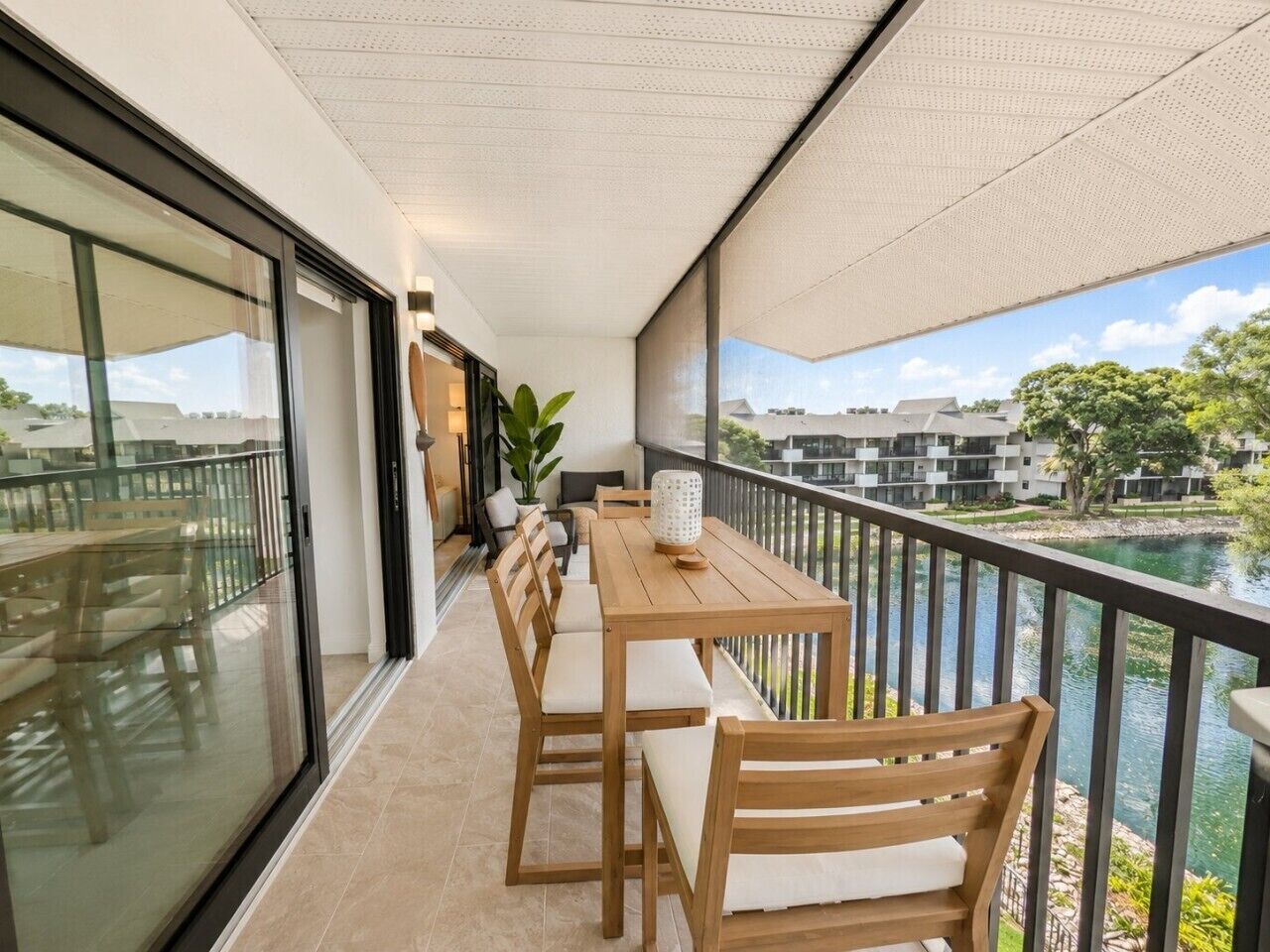 Un balcon avec une table et des chaises, donnant sur une étendue d’eau et des bâtiments.