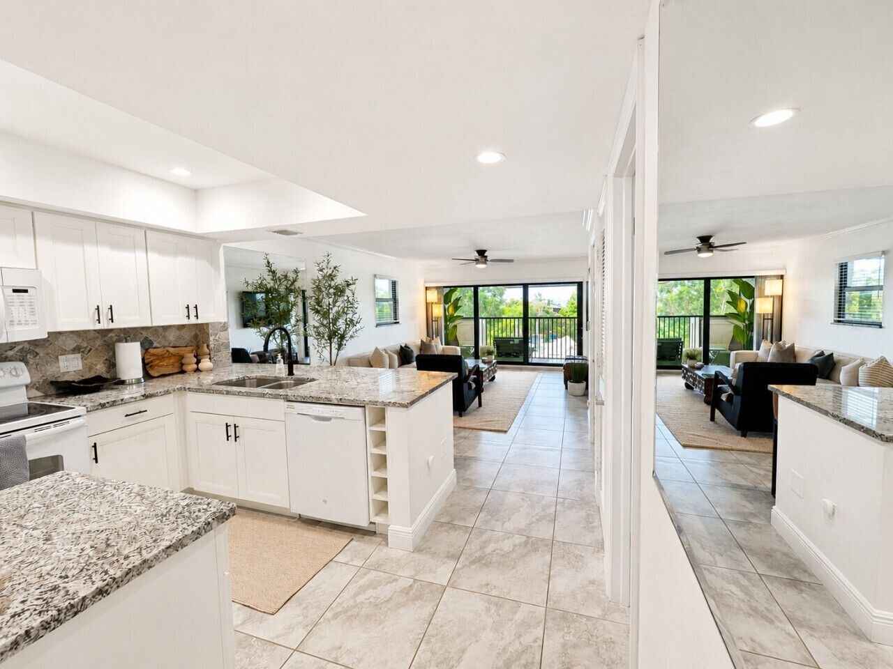 A modern kitchen with white cabinetry, granite countertops, and a central island.