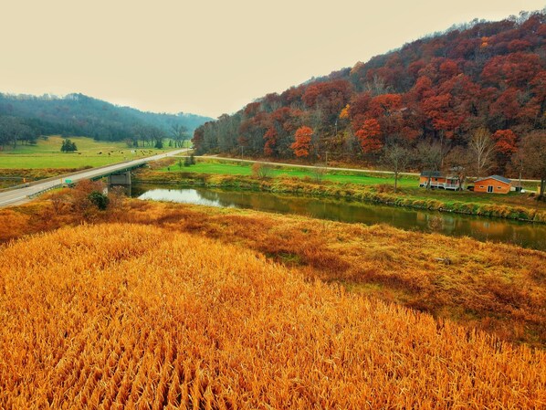A rural landscape with a river, fields, and a bridge.