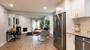 Una cocina moderna con electrodomésticos de acero inoxidable, un comedor con una mesa redonda y sillas, y una sala de estar con chimenea.