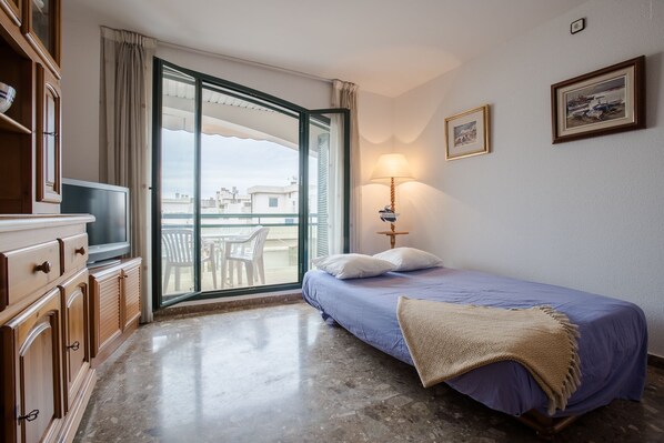 Una habitación de hotel con cama, televisión, lámpara y vistas al exterior.