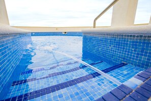 Una piscina con azulejos de mosaico azul y una vista despejada del cielo.