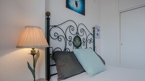 A neatly made bed with two pillows, a wall-mounted picture, and a bedside lamp. - Aiguadolç - Alojamientos MarCalma (Tarragona)