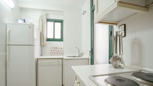 A compact kitchen with a refrigerator, dishwasher, sink, and stove. - Aiguadolç - Alojamientos MarCalma (Tarragona)