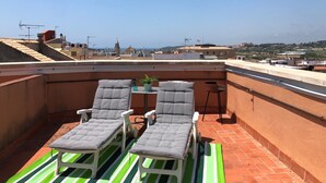 Une terrasse sur le toit, avec deux chaises longues et une petite table, d’où l’on peut admirer la vue sur la ville.