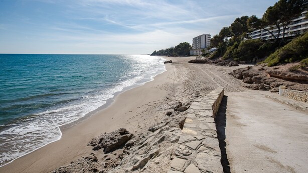 Une plage avec un sentier en pierre menant à un bâtiment doté de nombreux balcons.