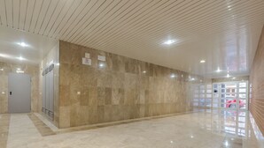 Un hall d’entrée spacieux avec un mur en marbre et un plafond en bois.