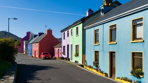 Une rangée de maisons aux couleurs vives, avec une voiture rouge garée devant.