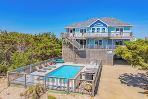 A two-story beachfront house with a pool, deck chairs, and a staircase leading to the upper level. - Semi-Oceanfront Home with Private Pool, Hot Tub, Game Room, Nearby Beach Access (Avon)