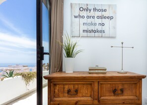 A wooden dresser with a potted plant, a decorative item, and a wall with a motivational quote.