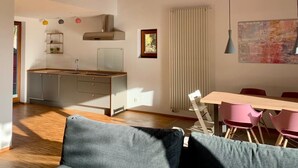 Una cocina moderna con encimera de madera y estufa integrada, un comedor con mesa y sillas, y un ventanal que proporciona luz natural.