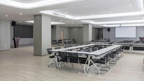 A modern conference room with multiple tables and chairs, a large screen, and a projector. - Jiasheng International Hotel (Jiayu)