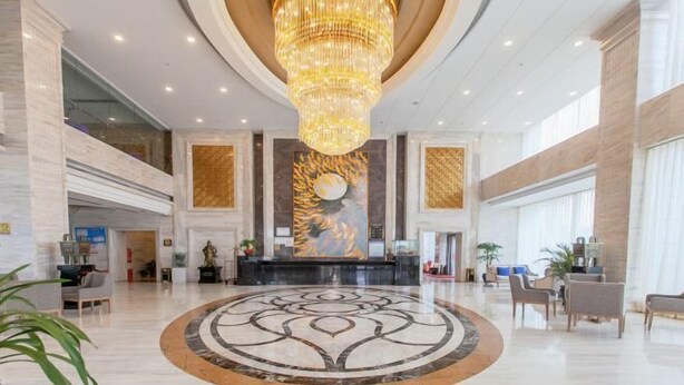 A spacious lobby with a large chandelier, a reception desk, and a circular floor design. - Jiasheng International Hotel (Jiayu)