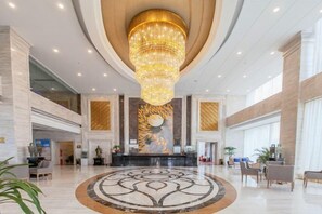 A spacious lobby with a large chandelier, a reception desk, and a circular floor design. - Jiasheng International Hotel (Jiayu)