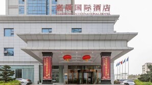 A modern hotel building with a prominent entrance, large windows, and a sign indicating it is the Jiaheng International Hotel. - Jiasheng International Hotel (Jiayu)