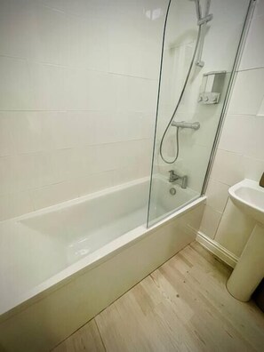 A modern bathroom with a glass-enclosed shower, a white bathtub, and a sink.