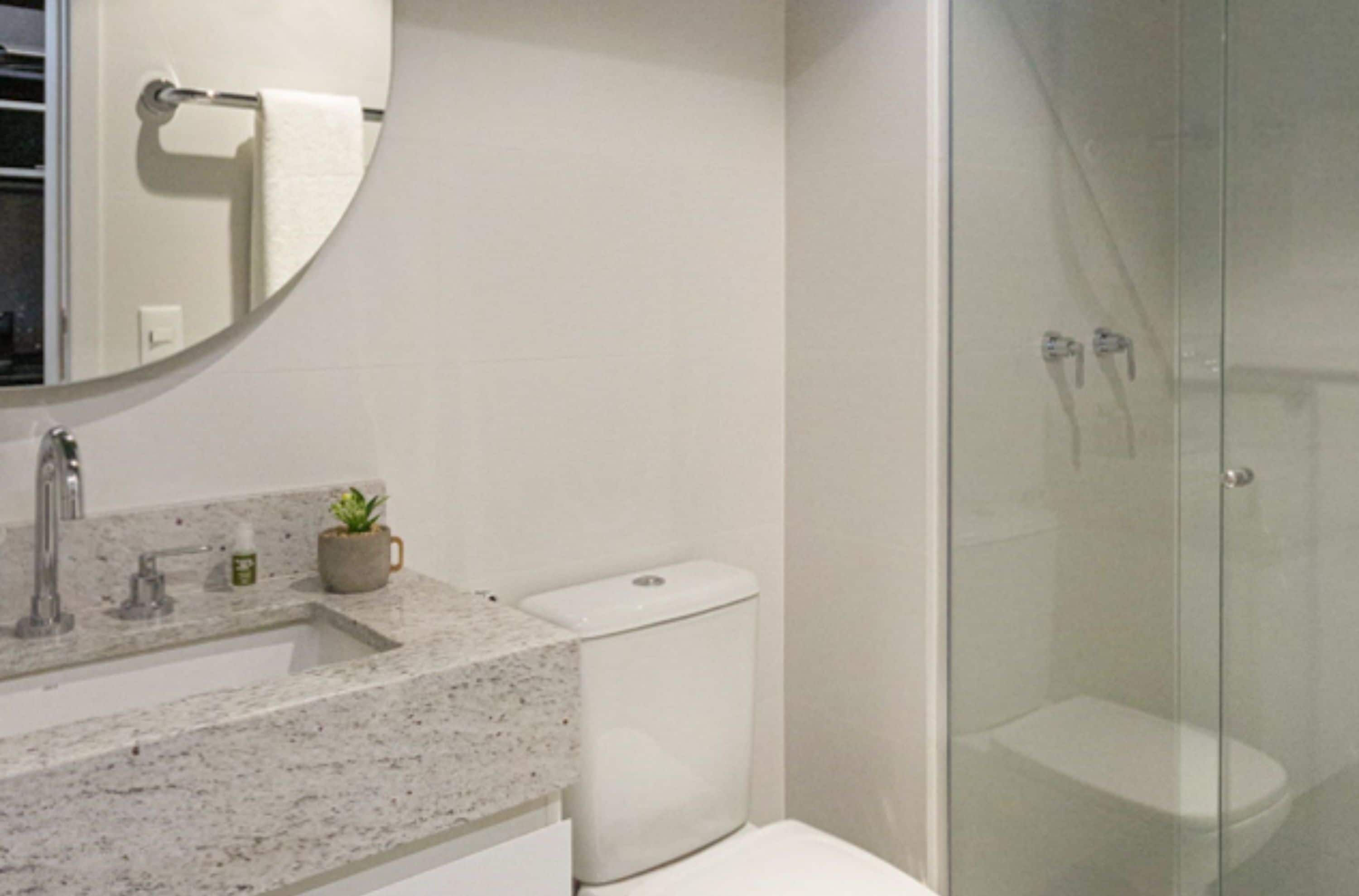 Une salle de bain dotée d’un comptoir en granit, de toilettes et d’une cabine de douche en verre.