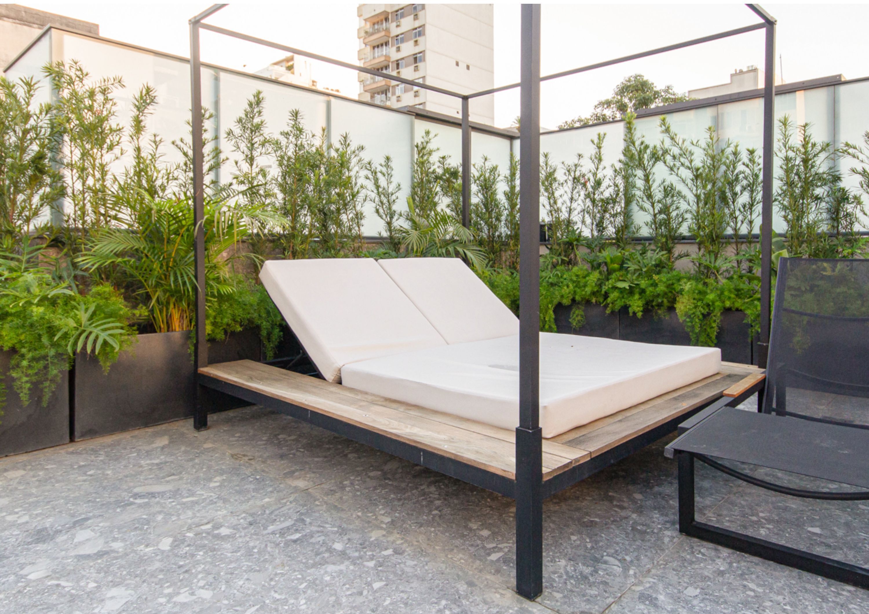 Jardim no terraço com estrutura de cama de metal e colchão.