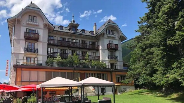 A hotel with a large building, outdoor seating, and a grassy area. - In the village of Evolène friendly sunny studio (Evolène)