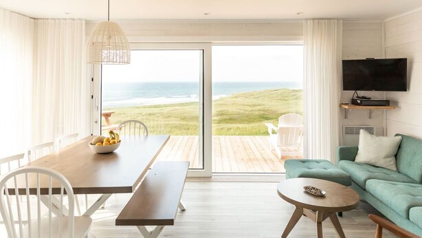 A modern living room with a large sliding glass door leading to a balcony with a view of the ocean.
