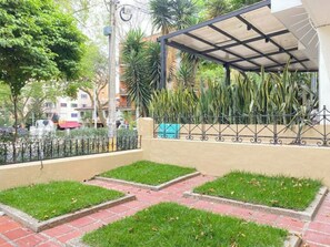 Stroll along the paved walkway to a serene seating area under a metal roof.