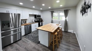 Een moderne keuken met roestvrijstalen apparatuur, een houten eiland en barstoelen.