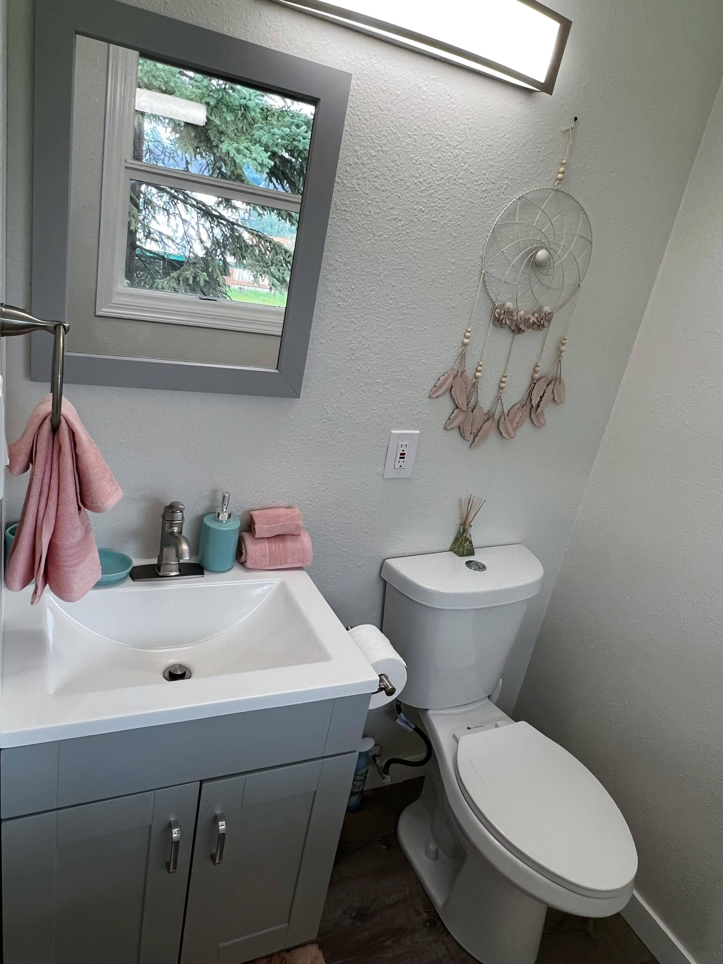 Ein Badezimmer mit Waschbecken, Toilette und Fenster.