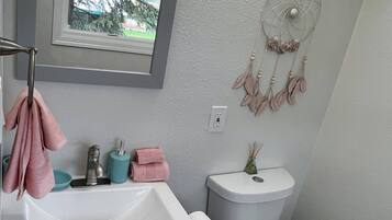 Ein Badezimmer mit Waschbecken, Toilette und Fenster.