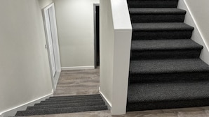 Een trap met donkere, beklede treden en een houten vloer als plateau.
